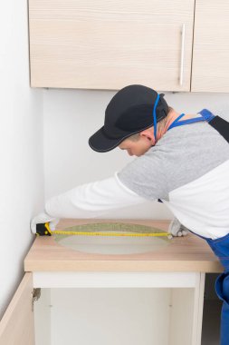 Usta, lavaboyu kurmadan önce bir mezura ile deliğin ölçümlerini yapar.