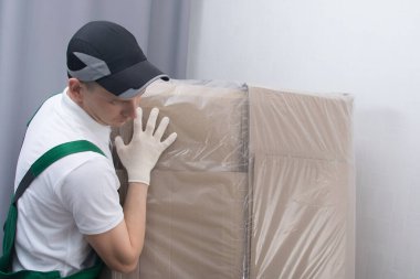 Büyük bir kutuyu elden taşıyan bir kuryenin yakın çekimi.