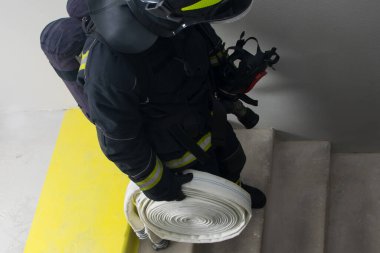 İtfaiyeci, elinde ekipmanla yanmayan merdivenlerden iniyor.