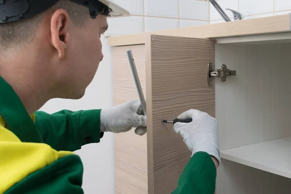 master kitchen furniture assembler, installs the handle on the kitchen cabinet door