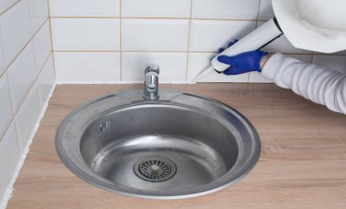 İç dekorasyon ustası, döşeme ve mutfak tezgahının eklemlerini etek tahtası yerine beyaz silikonla, lavabonun arka planına sürmüş.