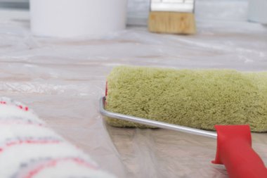 Beyaz bir duvara karşı, inşaat malzemelerinin yakın çekimi, boya ruloları