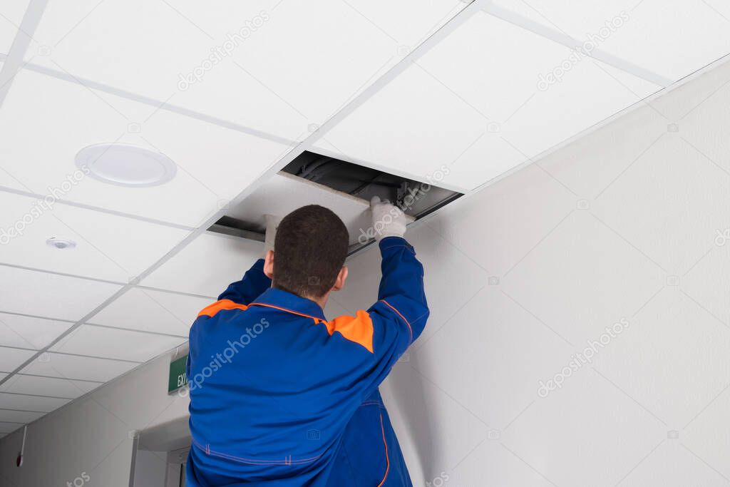 worker dismantles the suspended ceiling, rear view