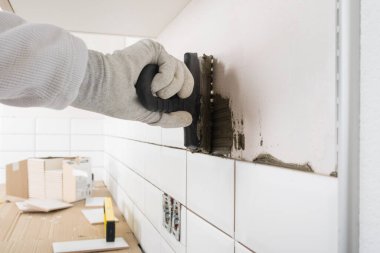 Beyefendinin eli seramik seramik seramik seramik döşemek için duvara havan topu sürüyor.