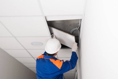 Miğferli bir işçi asılmış tavanı ve dikiz aynasını söker.