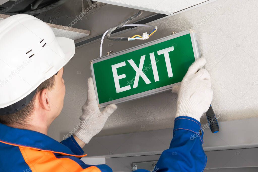 Foreman completes installation of lighting signs emergency exit