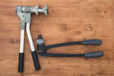 Yazmak için bir yeri olan ahşap bir yüzeyde plastik boru genişleticisi ve su boruları için bir pres var.