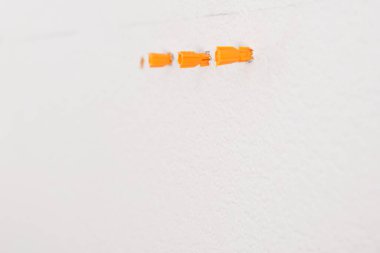 turuncu plastik tıkaçlar beton duvardaki deliklere yerleştirilmiş.