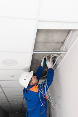 Bir işçi tel tutucuları tavana vidaladı.