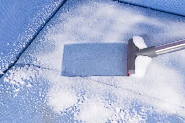 Elektrikli süpürge fırçası temizleme maddesini döşenmiş mobilyaların yüzeyinden çıkarır.