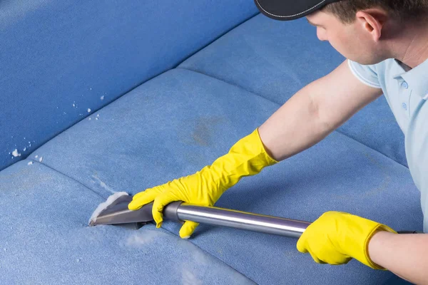Bir adam döşemelerin dikişlerini elektrikli süpürge ve özel bir sıvı temizleyiciyle temizler.