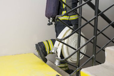 a firefighter goes down the stairs and carries a hose line and equipment for extinguishing fires in the room clipart