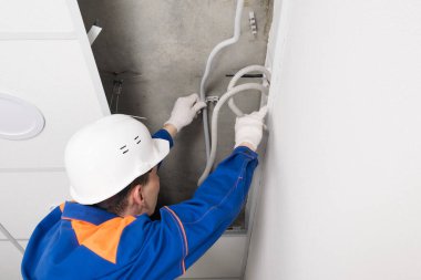 Miğferli bir işçi sahte tavana kablo yerleştirir.