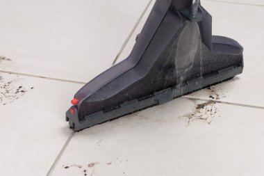 Kirli lekeli hafif fayans, elektrikli süpürge ile temizlik, yakın çekim.