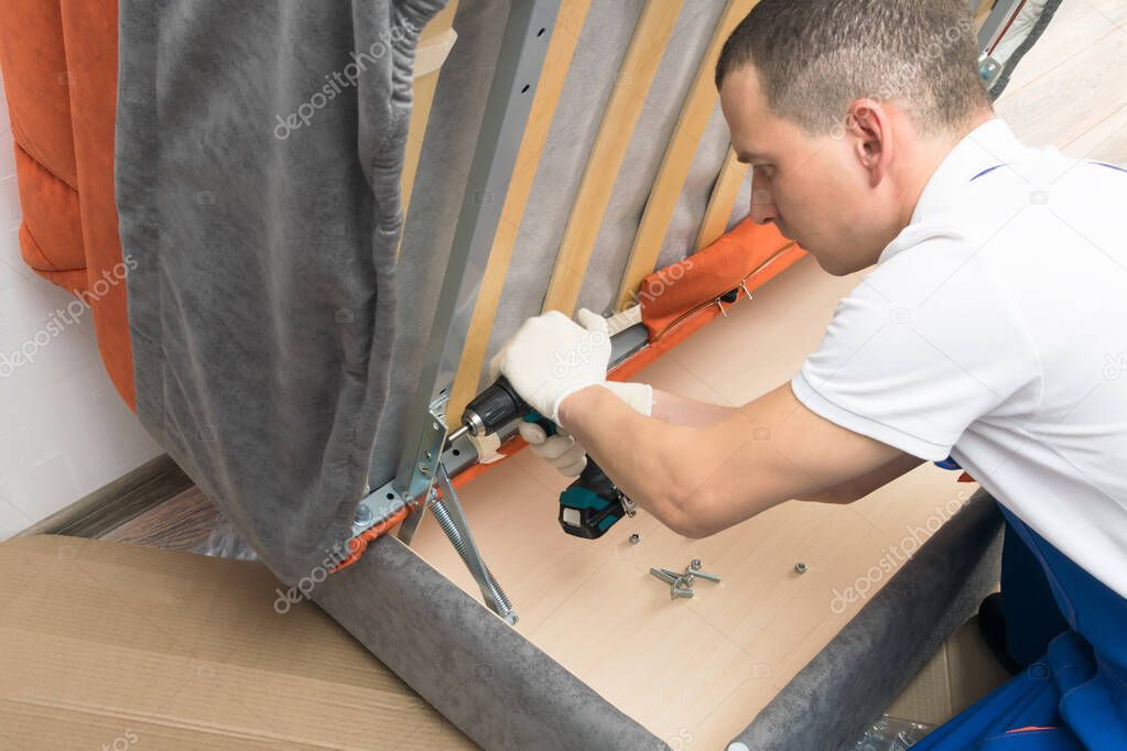 a furniture repair worker replacing the creaking mechanism of an upholstered sofa