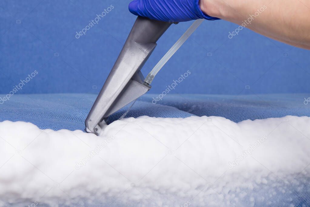 cleaning vacuum cleaner, using a brush, close-up, collects a thick white foam, after removing stains, from textiles