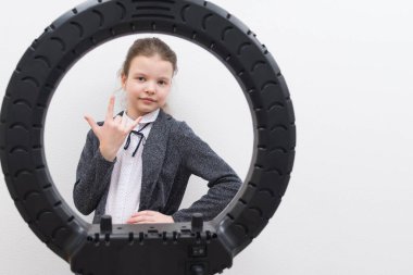 Gri ceketli bir kız, dairesel bir lambanın ortasında, üç parmağını gösteriyor, yazıtlar için bir yer var.