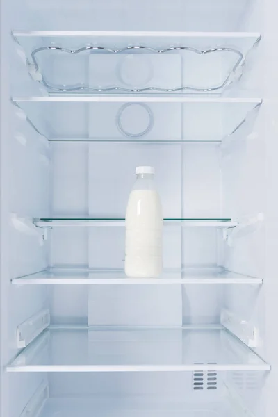 a bottle of milk in the refrigerator, on a glass shelf, on a white background