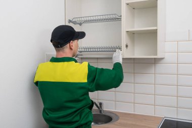 Mutfak mobilyaları montajcısı üst dolapları ve dikiz manzarasını monte ediyor.