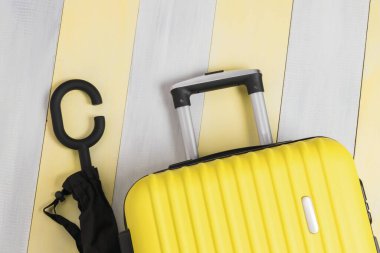 Gri-sarı arka planda şemsiye ve sarı seyahat valizi