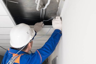 Usta ofisteki sahte tavanda ağ kablosunu çalıştırıyor.