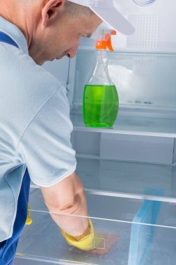 Buzdolabını temizliyor. Adam dezenfeksiyon yapıyor.