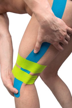 Beyaz arka planda, Kinesio bantlı bir adamın bacağı, rahat spor olsun diye yapıştırılmış.