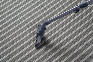 Çizgili halının arka planında, ıslak temizleme için elektrikli süpürge fırçası, yazıtlar için bir yer var.