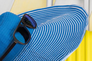 Sarı valizli mavi büyük şapka ve güneş gözlüğü, yakın plan.