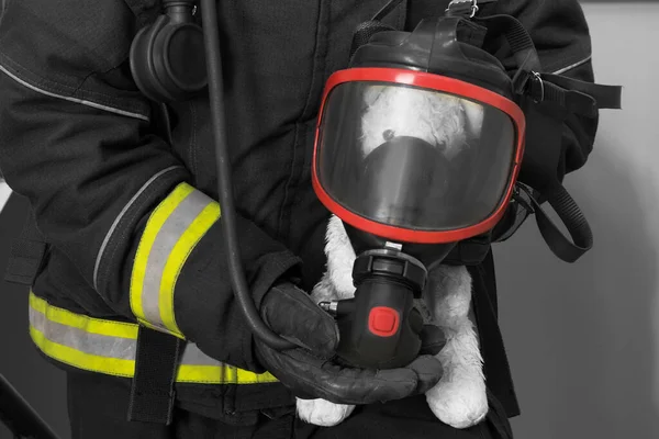 在火灾中教育孩子的概念 消防员手里拿着一个戴着呼吸面罩的泰迪熊 — 图库照片