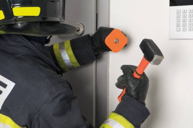 firefighter trying to open an iron door with a sledgehammer, rear view clipart