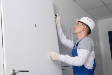 Üniformalı bir marangoz, ön kapının menteşelerini ayarlar, yazıtlar için bir yer vardır.