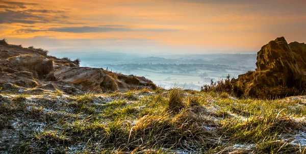 Always & Forever - Warm glow of sunrise shining on rugged rocks before clearing the mist across the miles of low land — Stock Photo, Image