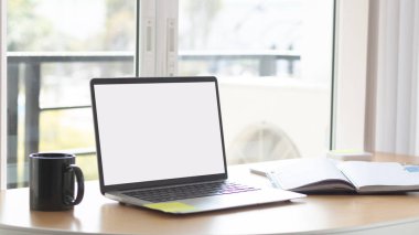 Çalışma masasında beyaz boş ekranlı dizüstü bilgisayar ve uzay konseptini kopyala