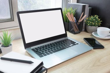 Çalışma masasında beyaz boş ekranlı dizüstü bilgisayar ve uzay konseptini kopyala