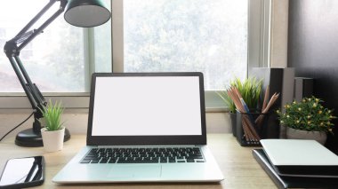 Çalışma masasında beyaz boş ekranlı dizüstü bilgisayar ve uzay konseptini kopyala