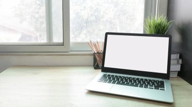Çalışma masasında beyaz boş ekranlı dizüstü bilgisayar ve uzay konseptini kopyala