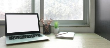 Çalışma masasında beyaz boş ekranlı dizüstü bilgisayar ve uzay konseptini kopyala