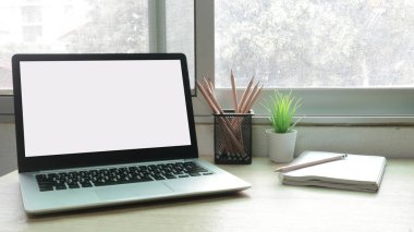 Çalışma masasında beyaz boş ekranlı dizüstü bilgisayar ve uzay konseptini kopyala