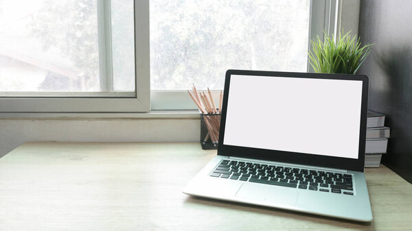 Laptop computer with white blank screen on desk in workspace and copy space concept