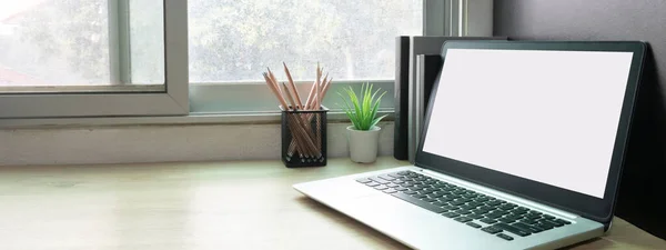 Laptop computer with white blank screen on desk in workspace and copy space concept