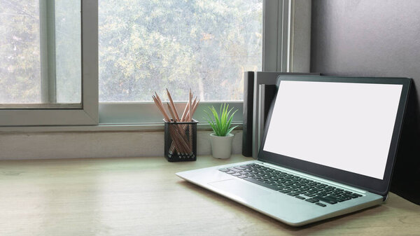 Laptop computer with white blank screen on desk in workspace and copy space concept