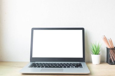 Çalışma masasında beyaz boş ekranlı dizüstü bilgisayar ve uzay konseptini kopyala