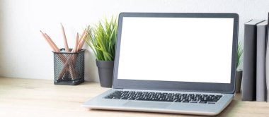 Ahşap masadaki beyaz ekranlı dizüstü bilgisayar. Çalışma alanı, işyeri, masaüstü ofis kavramı.