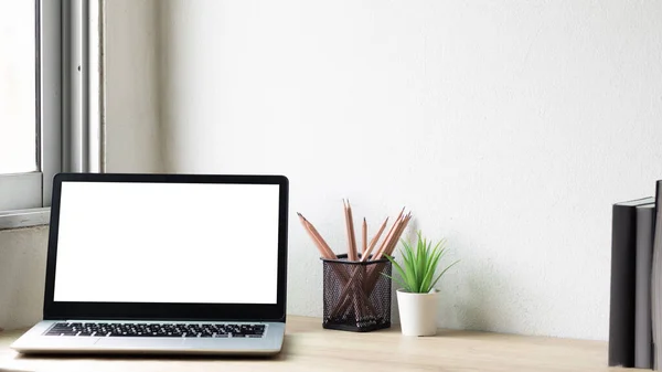 Laptop computer with white blank screen on wood desk. Workspace, workplace, desktop office concept.