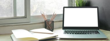 Çalışma masasında beyaz boş ekranlı dizüstü bilgisayar ve uzay konseptini kopyala