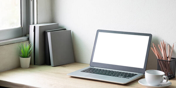 Laptop computer with white blank screen on desk in workspace and copy space concept