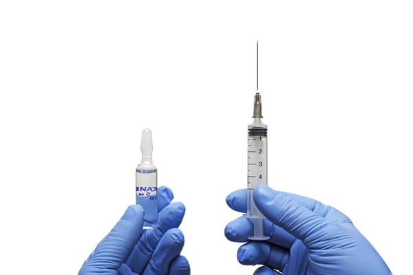 Medical gloved hand holding syringe with a bead of liquid emerging testing the function of the syringe — Stock Photo, Image
