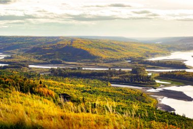 Sarı ve yeşil sonbahar yapraklı ormanlarla çevrili vadideki tepeden nehre bakın. Sagitawa gözcüsü, Peace River, Alberta, Kanada.