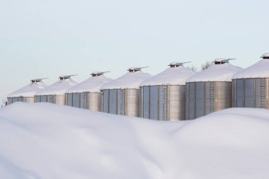 Soğuk kış mevsiminde tohum depolayan tarım çeliği kutuları. Çiftlikte ve kar yağdıktan sonra tahıl ambarlarında kar yığınları. Sabah yumuşak ışıkta en az.